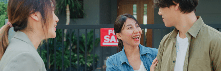 Young Asian woman real estate broker showing house to client buyers outside at home